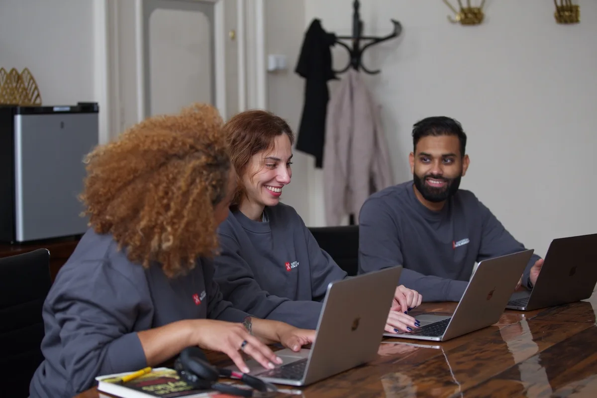 Drie studenten van Amsterdam Data Academy werken samen op laptops tijdens een AI-cursus