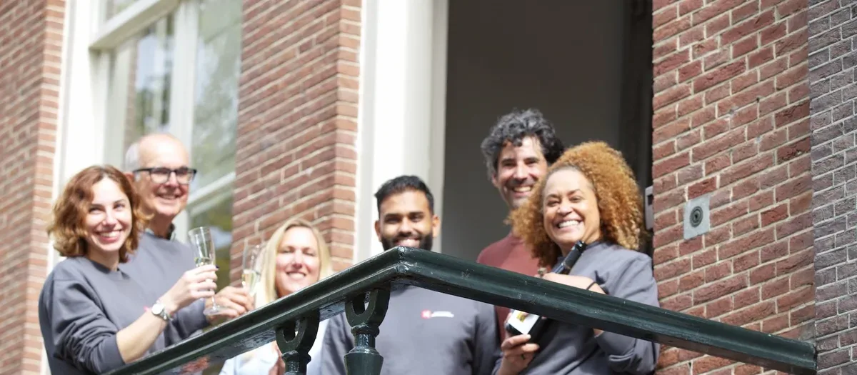 Amsterdam Data Academy alumni celebrating together outside a classic Amsterdam building