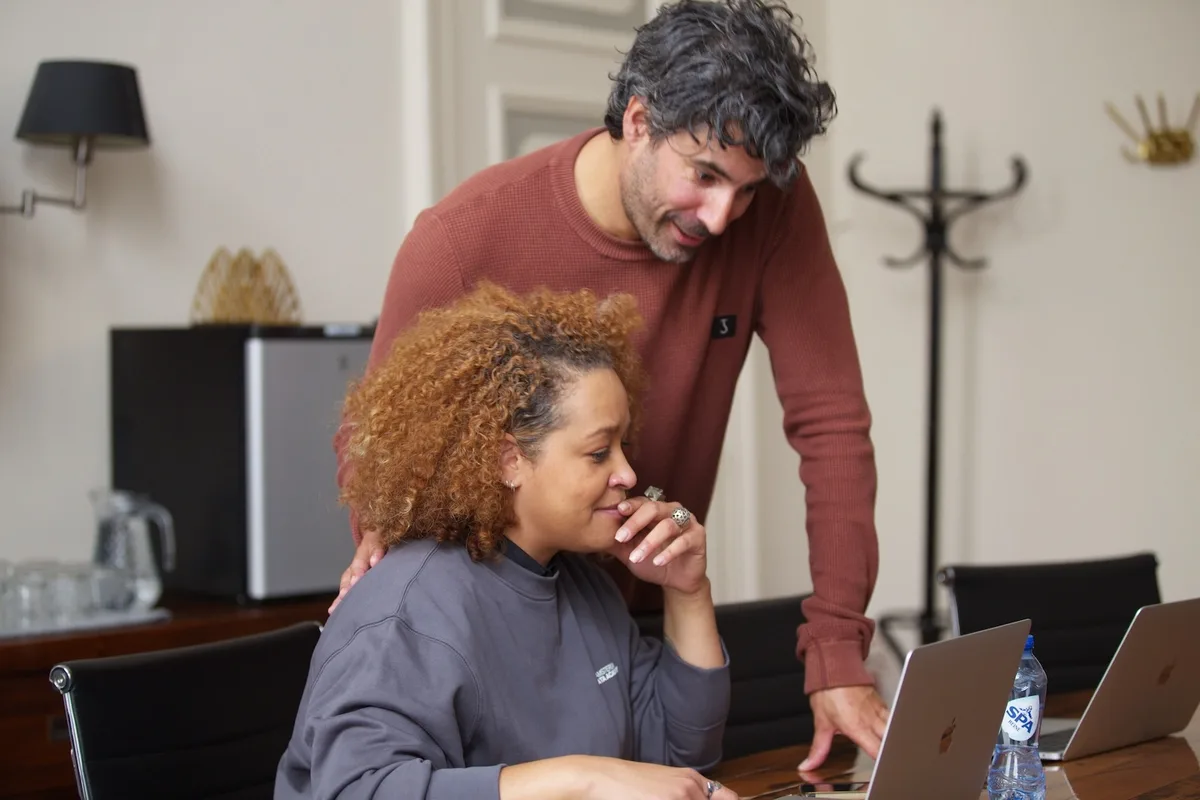 Een docent van Amsterdam Data Academy begeleidt een datastudent achter een laptop